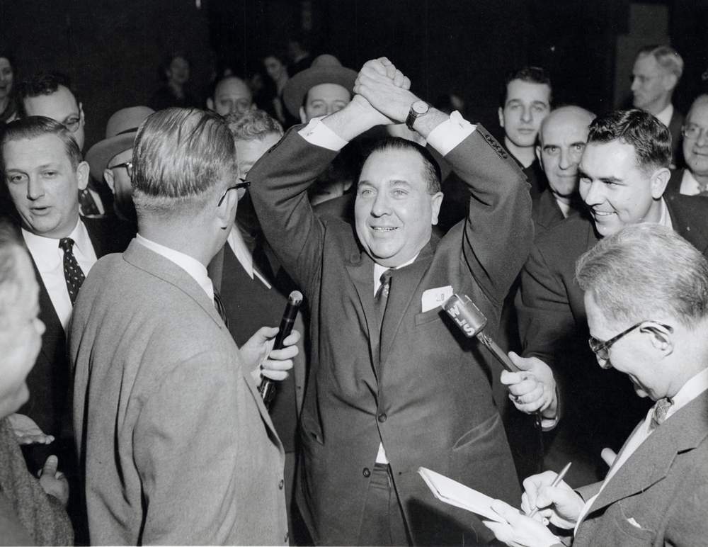 Richard J. Daley raises his arms in celebration after winning the 1955 mayoral election. (Courtesy of Special Collections &amp;amp; University Archives, RJD040100120002_025, University of Illinois at Chicago Library, Richard J. Daley Collection)