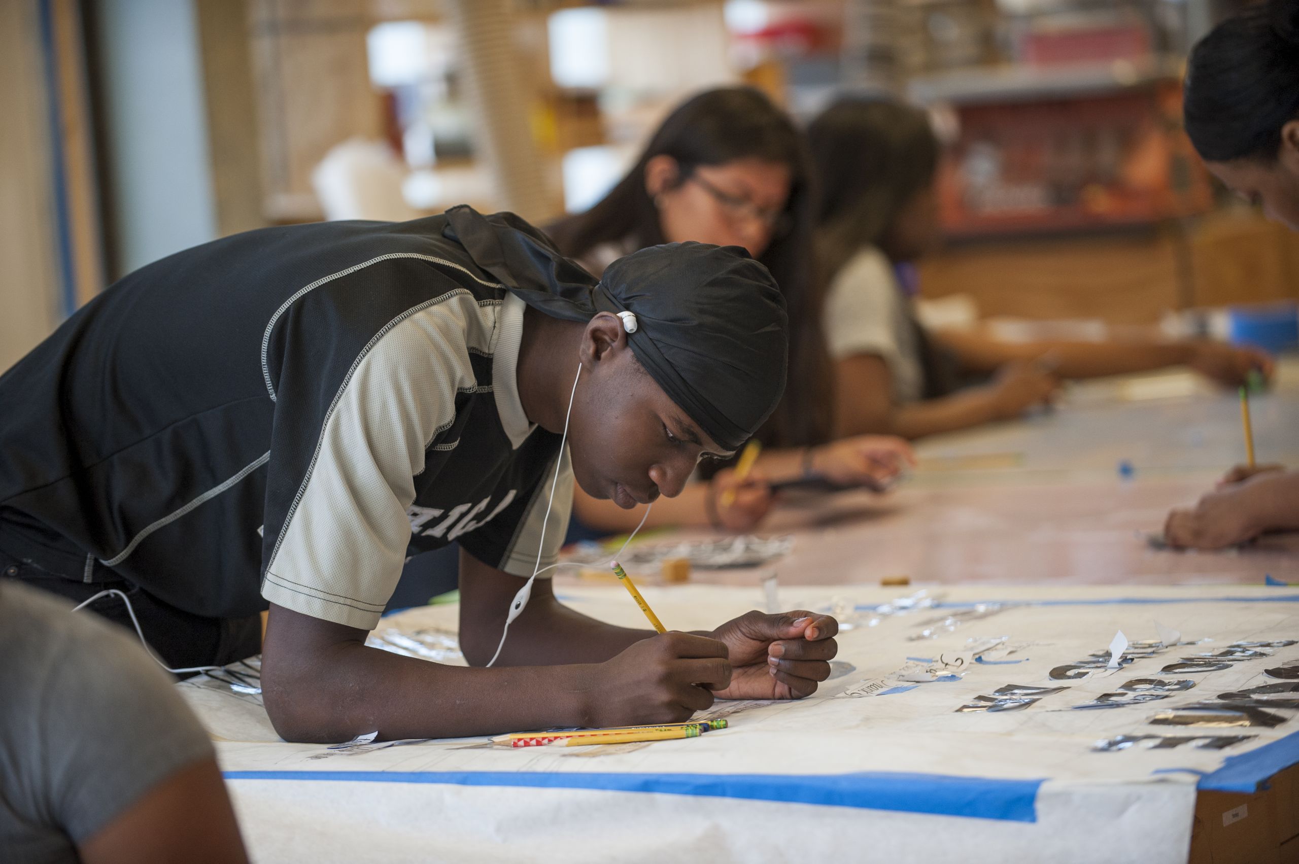 A young man draws on a sign in pencil.