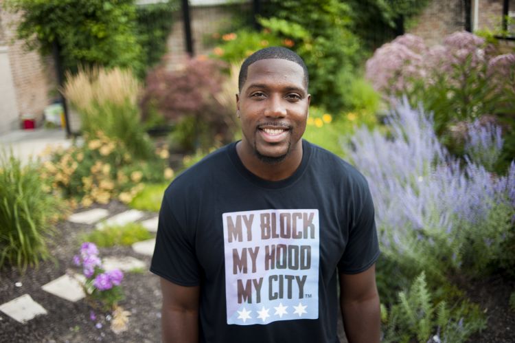 Jahmal Cole stands in a garden wearing a "My Block, My Hood, My City" t-shirt.
