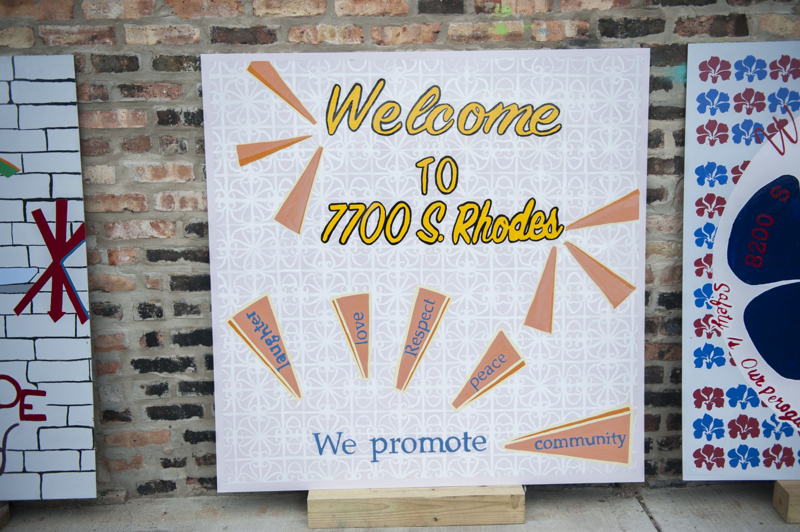 A sign is painted with green leaves around the border. In the center, written in blue, it says: "Welcome 1400 W 72nd Place." The words Respect and Love sit next to a drawing of a man captioned Mr. Jones.