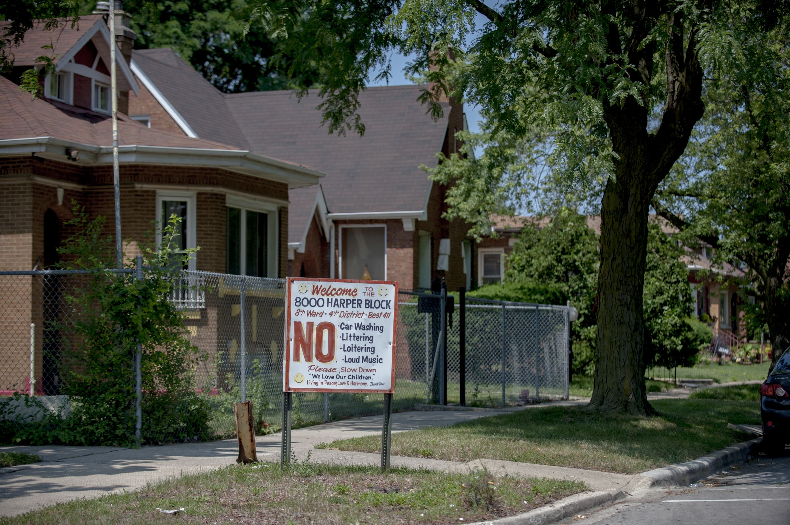 A sign with a large red NO on the left side. Brick houses stand behind it.