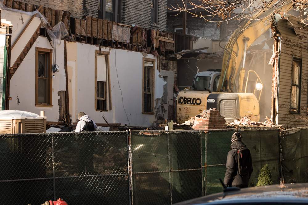 An Uptown resident watches as a residential building is torn down. There is no wet down of the debris. (City Bureau/Manny Ramos)
