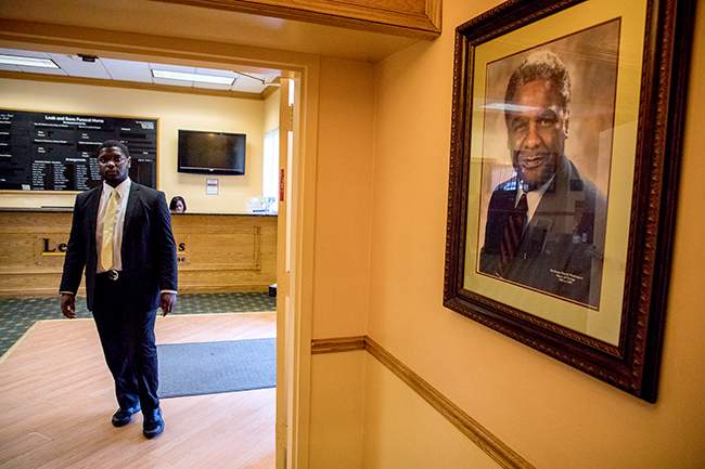 Mosley walks through the lobby of Leak &amp;amp; Sons, where a portrait of the late Chicago Mayor Harold Washington hangs. (Andrew Gill\/WBEZ)