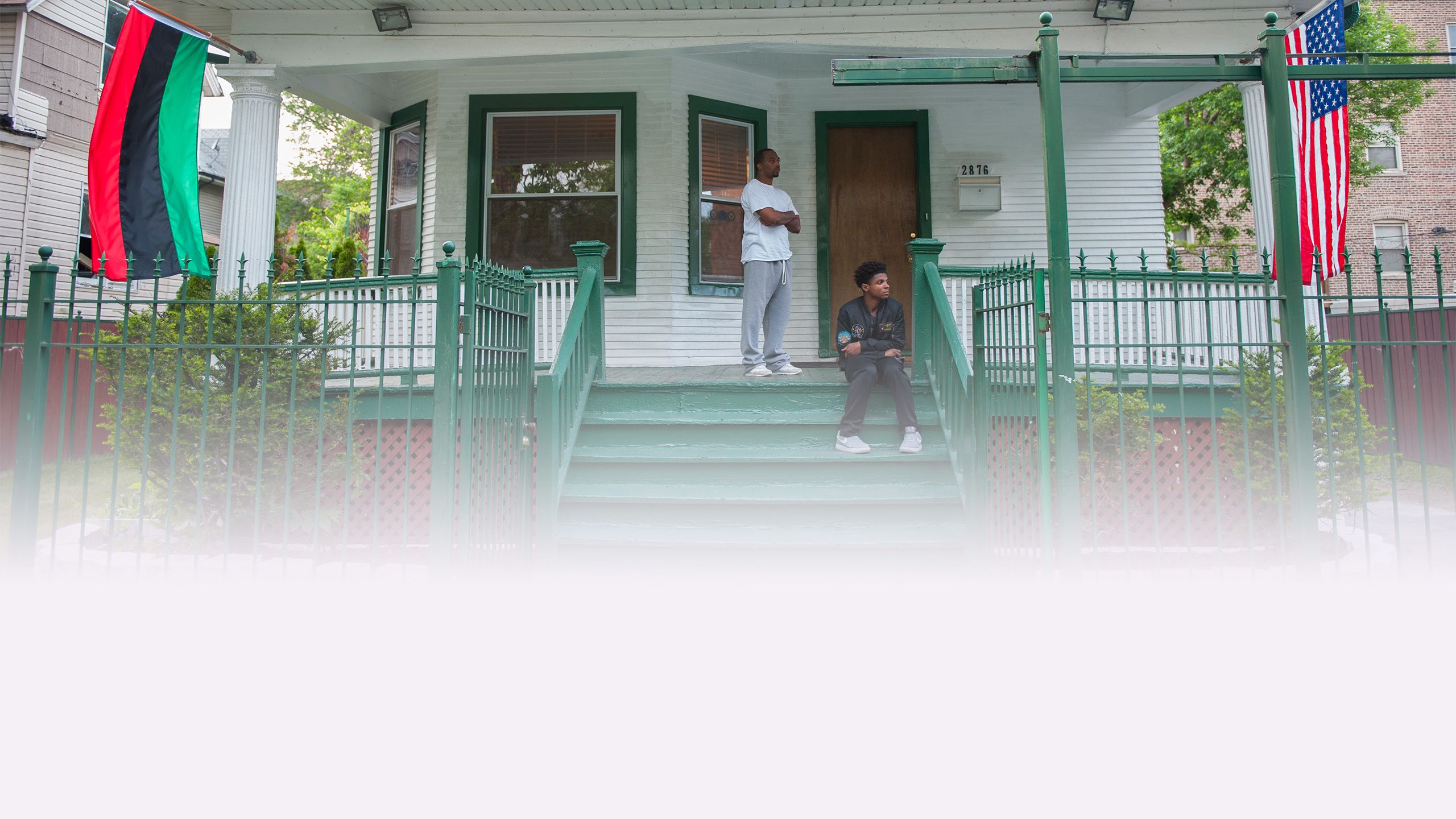 Two men on the porch of Hamilton House, a white house painted with green trim.