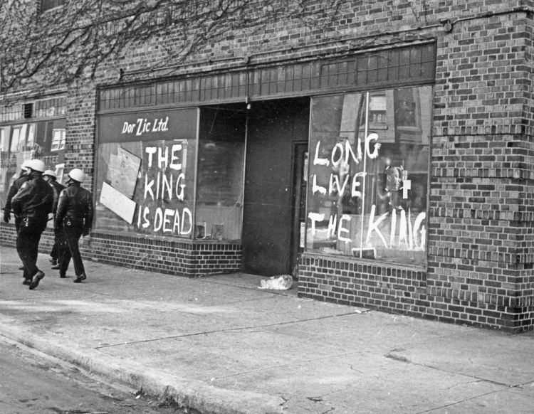 A window with the words "The King Is Dead, Long Live The King" painted on it in white.